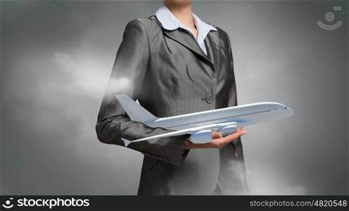 Aircraft or business travel concept. Close up of businesswoman hands holding airplane model