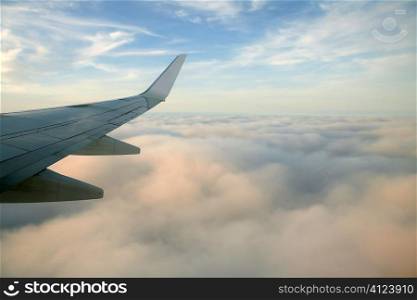 Aircraft right side wing, airplane flying over clouds in a blue sky day