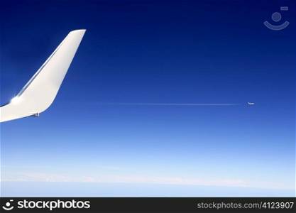Aircraft wing detail flying high up in deep blue sky