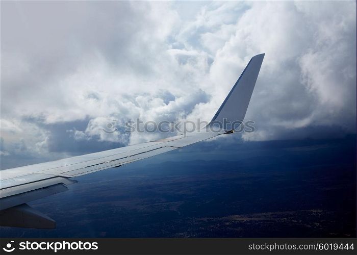Aircraft wing in a cloudy stormy clouds sky flying