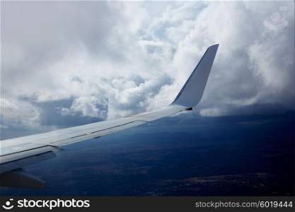 Aircraft wing in a cloudy stormy clouds sky flying