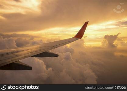 Aircraft wing on the clouds of sunset ,flying traveling background