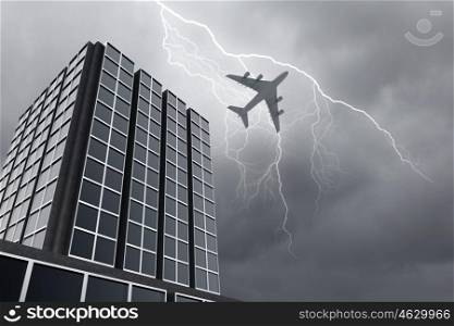 Airplane above city. Bottom view of airplane flying above skyscraper in stormy sky