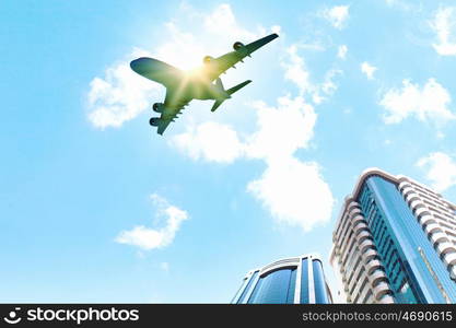 Airplane above city. Image of airplane flying above skyscrapers. Bottom view