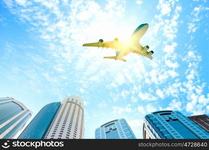 Airplane above city. Image of airplane flying above skyscrapers. Bottom view