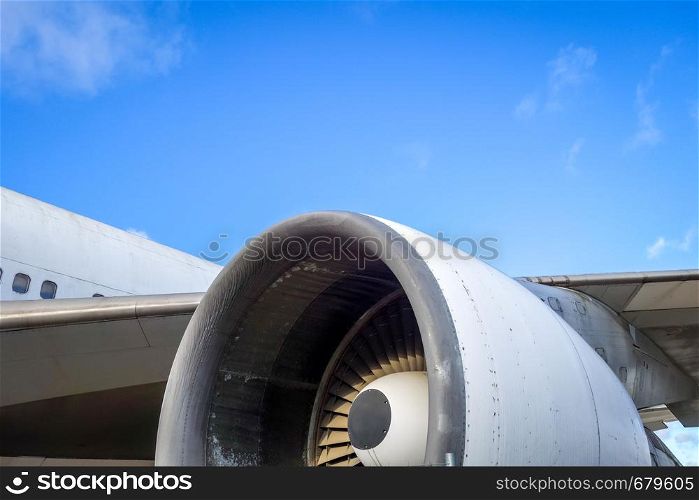 Airplane engine and wing on airport tarmac. Blue sky. Airplane engine and wing