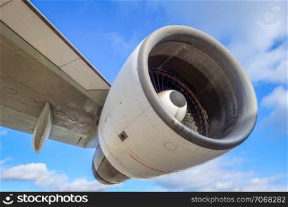 Airplane engine and wing on airport tarmac. Blue sky. Airplane engine and wing