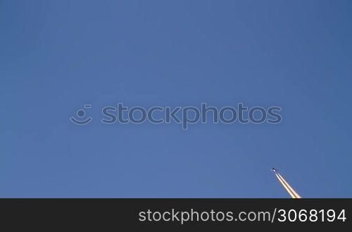 Airplane flies overhead on clear, blue sky