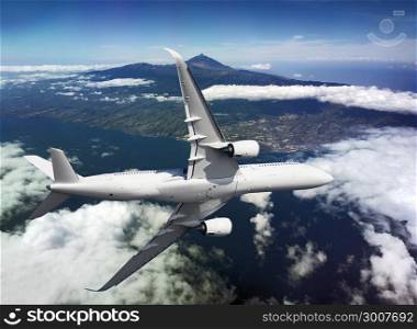 Airplane flying over the island and mountains with a clouds