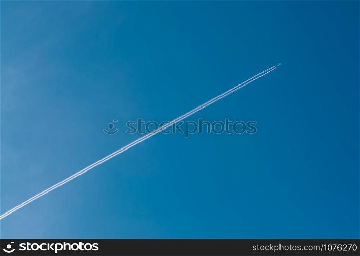 Airplane flying through clear blue sky with vapour trails