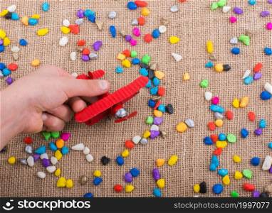 Airplane in hand amid colorful pebbles on canvas