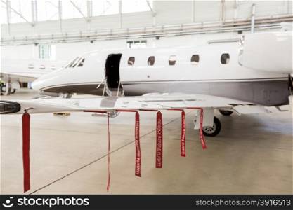Airplane in Hangar with remove before flight Labels in red. Airplane in Hangar with remove before flight Labels in red warning safety