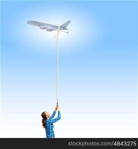 Airplane in sky. Young woman in casual catching flying airplane with rope