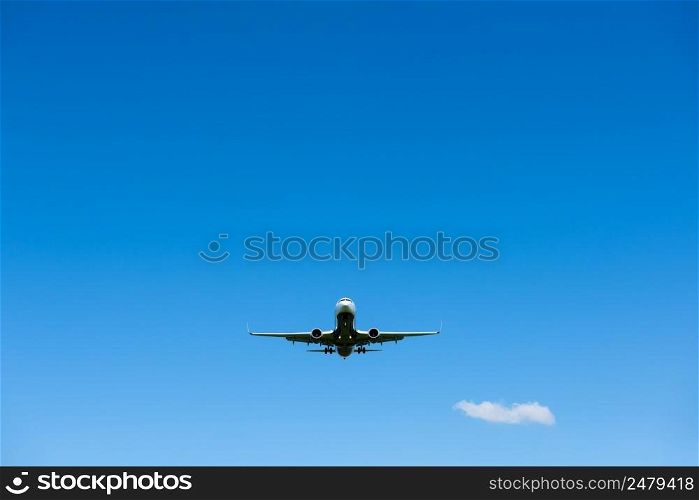 Airplane in the clear blue sky, preparing to landing, front view from the ground