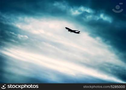 Airplane in the sky, silhouette of a big airliner over blue overcast sky background, luxury travel and journey, expensive transport