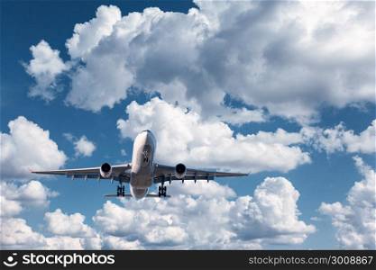 Airplane. Landscape with white passenger airplane is flying in the blue sky with clouds at sunny day. Travel background. Passenger airliner at sunrise. Business trip. Commercial plane. Aircraft. Jet