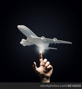 Airplane model. Human hand pointing with finger at airplane