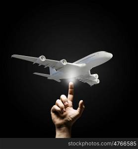 Airplane model. Human hand pointing with finger at airplane