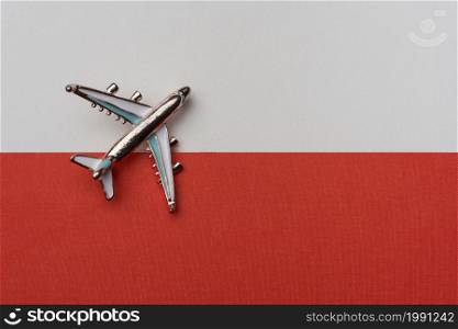 Airplane over the flag of Poland, the concept of travel. Toy airplane on the flag as a background.. Airplane over the flag of Poland, the concept of travel.