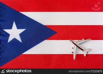 Airplane over the flag of Puerto Rico travel concept. Toy plane on a flag in the background.. Airplane over the flag of Puerto Rico travel concept.
