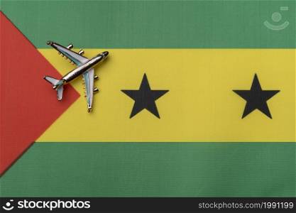 Airplane over the flag of Sao Tome and Principe, travel concept. Toy plane on the flag as a background.. Airplane over the flag of Sao Tome and Principe, travel concept.