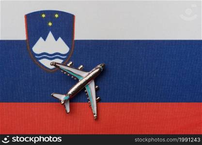 Airplane over the flag of Slovenia, the concept of travel. Toy airplane on the flag as a background.. Airplane over the flag of Slovenia, the concept of travel.