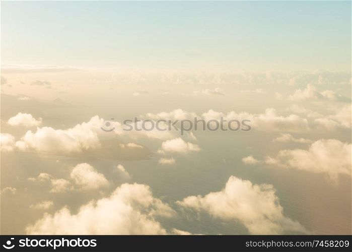 Airplane view of beautiful landscape with blue sky, gold colored clouds and ocean at sunny day