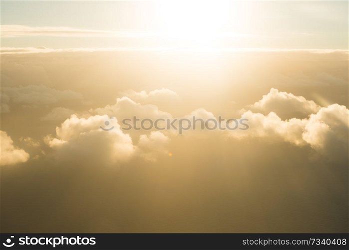 Airplane view of beautiful landscape with gold colored clouds, ocean and bright shining sun