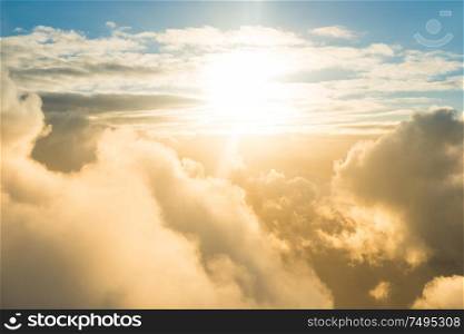 Airplane view of beautiful landscape with gold colored clouds, ocean and bright shining sun
