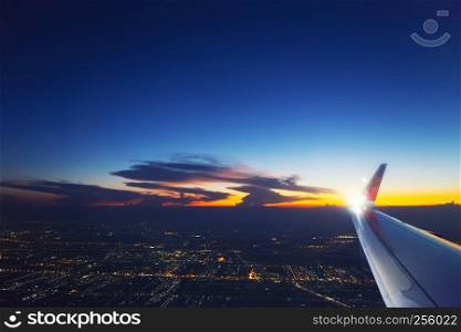 Airplane wing in the sky with cloud at sunset. Transportation, travel concept.