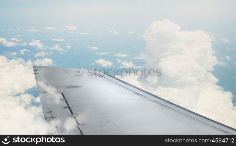 Airplane wing out of window. Flying airplane viewed from illuminator in blue sky