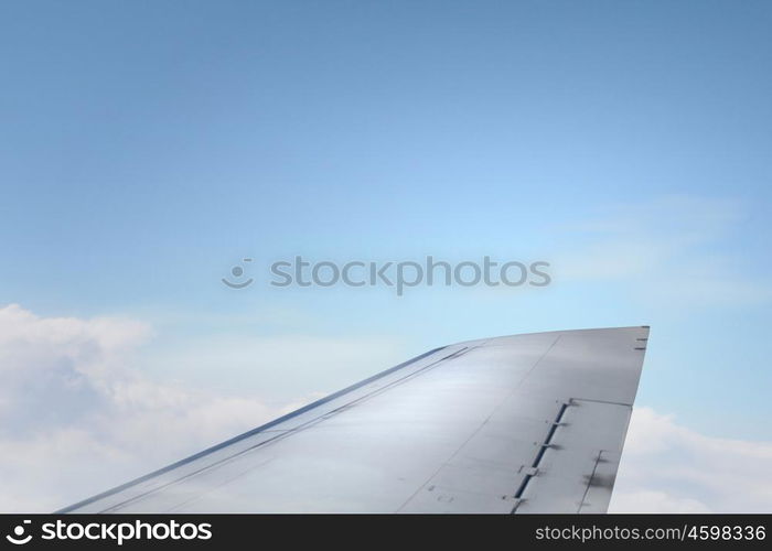 Airplane wing out of window. Flying airplane viewed from illuminator in blue sky