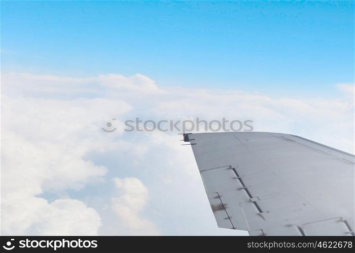 Airplane wing out of window. Flying airplane viewed from illuminator in blue sky