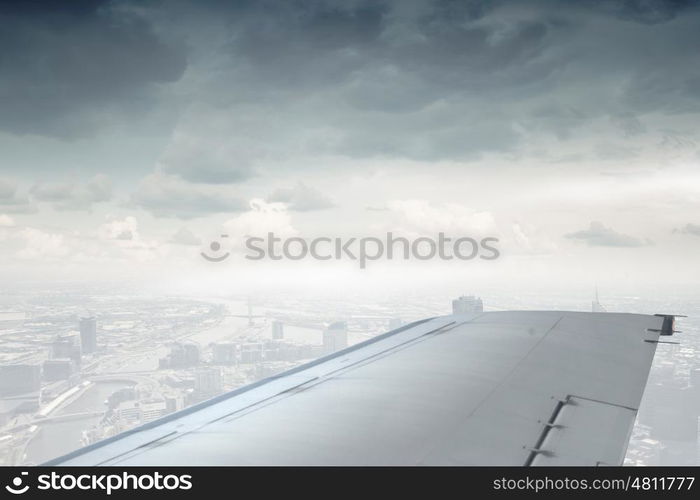 Airplane wing out of window. Flying airplane viewed from illuminator in blue sky