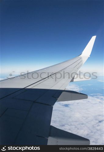 airplane wing with blue sky and white clouds as background