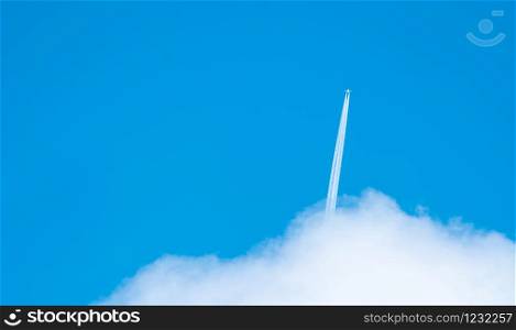 Airplane with white condensation tracks. Jet plane on blue sky and white clouds with vapor trail. Travel by airplane concept. Trails of exhaust gas from airplane engine. Aircraft with white stripes.