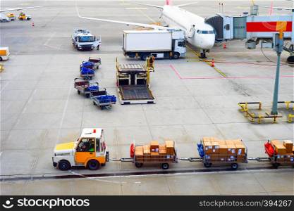 Airplanes, gangway, truck, parcels carrier, luggage carts at airport runway, aerial view