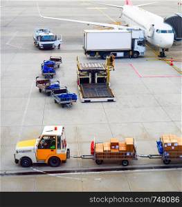 Airplanes, gangway, truck, parcels carrier, luggage carts at airport runway, aerial view