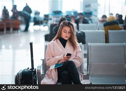 Airport business woman waiting in terminal. Air travel concept with casual businesswoman sitting with suitcase. Mixed race female professions.. Airport business woman waiting in terminal.