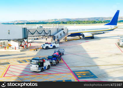 Airport scene, gangway to airplane, service loader cars carrying luggage by airfield, Madrid, Spain