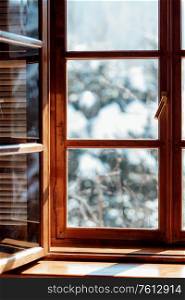 ajar window of a wooden house with seed on a snowy landscape