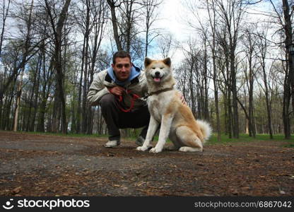 Akita inu female and young man posing in public park