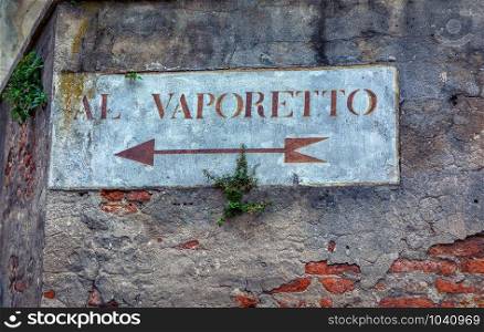 Al Vaporetto, venetian water bus. Old road sign with plants on a wall in Venice. Written in Italian