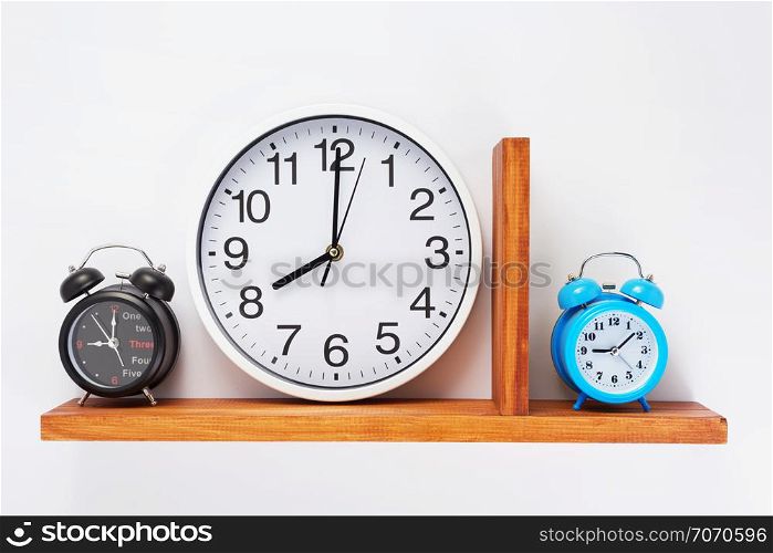 alarm and wall clock at wooden shelf on white background