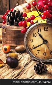 alarm clock and autumn symbols. Retro clock, fallen autumn leaves, pine cone, acorn and viburnum