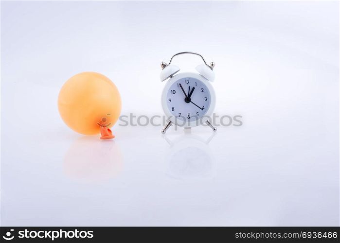 Alarm clock and colorful small balloon on a white background