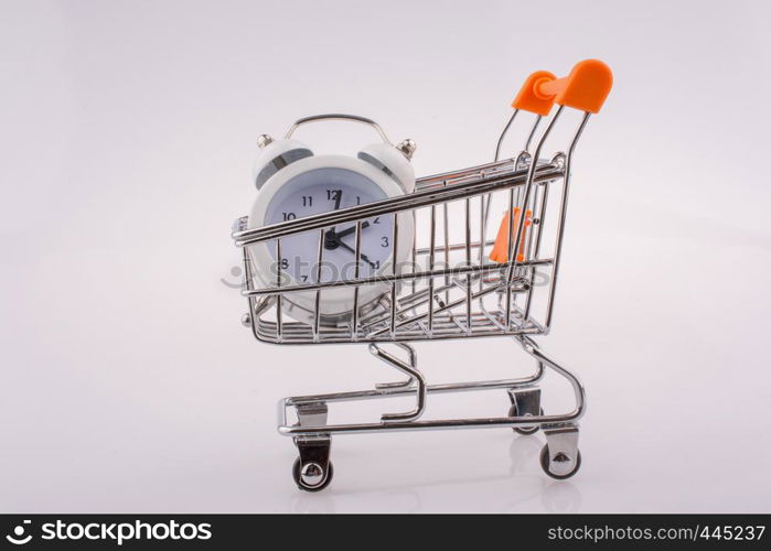 Alarm clock in a shopping trolley on white background