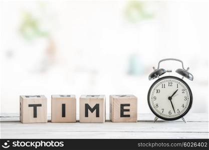 Alarm clock on a wooden desk with the word time