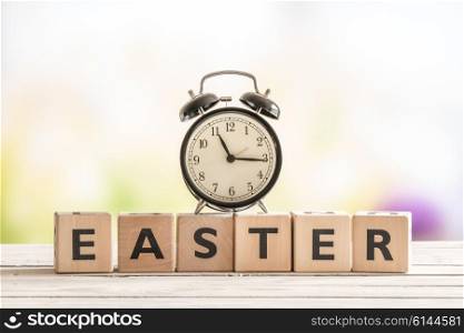 Alarm clock on a wooden easter sign in a garden