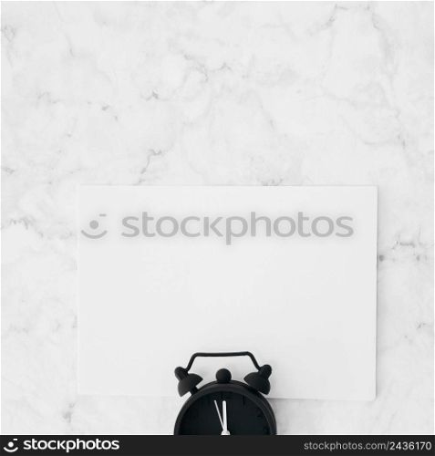 alarm clock white blank paper against marble textured background